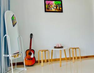 Habitación con guitarra, mesa y taburete en Kenppi HOMESTAY, en Hue