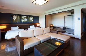 uma sala de estar com um sofá e uma cama em GRANDVRIORESORT ISHIGAKIJIMA Ocean's Wing & Villa Garden em Ishigaki