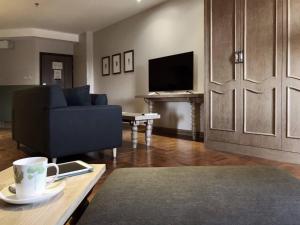 a living room with a couch and a tv and a table at The Raintree Hotel Chiang Mai in Chiang Mai