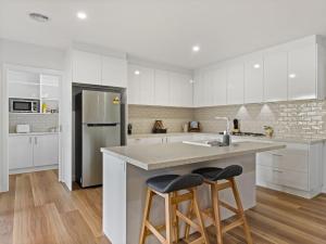 a kitchen with white cabinets and a island with two bar stools at Rosella Retreat in Yarrawonga +7 photos