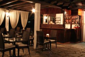 a restaurant with tables and chairs and a bar at Vicky Rooms & Apartments in Limenas