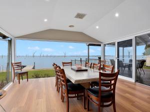 a dining room with a table and chairs and a view of the water at Lakeside Mulwala in Mulwala