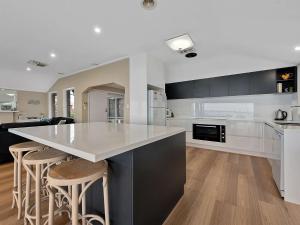 a kitchen with a large white counter and stools at Lakeside Mulwala in Mulwala