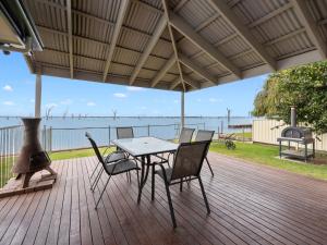 a table and chairs on a deck with a view of the water at Lakeside Mulwala in Mulwala