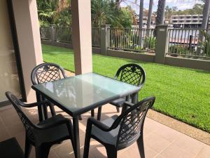 a glass table and chairs on a porch with a lawn at Cypress 39 A in Mulwala