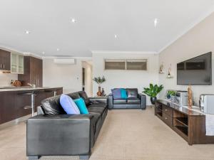 a living room with a black leather couch and a kitchen at Cypress 39 D in Mulwala