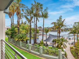 a balcony with palm trees and a body of water at Cypress 39 D in Mulwala