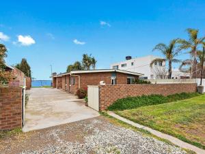 a brick building with a fence and a driveway at Waterside Mulwala in Mulwala
