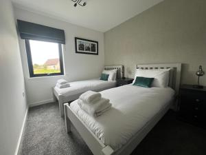 a bedroom with two beds and a window at The Peaks Three Bed Apartment in Aviemore