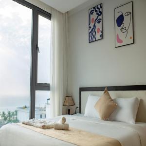 a white bedroom with a large bed with a window at KIKOZO DA NANG Hotel in Da Nang