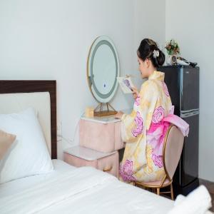 una mujer en un kimono sentada frente a un espejo en KIKOZO DA NANG Hotel, en Da Nang