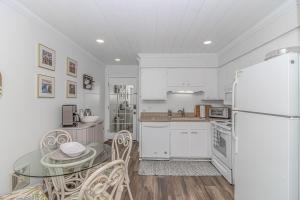 a white kitchen with a table and a refrigerator at Cozy Condo, Beach Access, Dock, Pool, Sunsets in Myrtle Beach