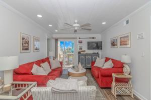 a living room with red couches and a ceiling fan at Cozy Condo, Beach Access, Dock, Pool, Sunsets in Myrtle Beach