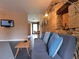 ein Wohnzimmer mit einem blauen Sofa und einer Steinmauer in der Unterkunft Gîte Leymen, 2 pièces, 2 personnes - FR-1-744-7 in Leymen