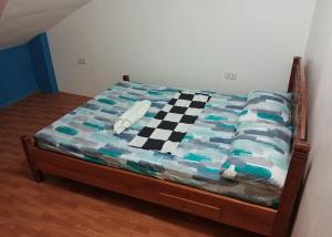 Cama en habitación con colcha a cuadros en Footprints Hostel en Corón