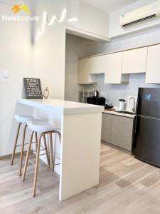 a kitchen with white cabinets and a black refrigerator at Costa Mahkota Suites Malacca Central By Nestcove in Melaka