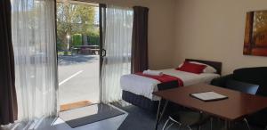 a room with a bed and a table and a window at Commodore Motor Lodge in Ashburton
