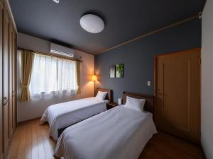 een hotelkamer met 2 bedden en een raam bij 1組限定　1棟貸切 「おとまり忠左衛門」　 グループや3世代旅行に最適　　　　 in Ikeda