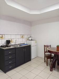 a kitchen with a table and a sink and a refrigerator at Paradise Celeste in Bijagua