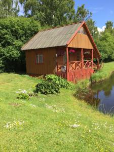 a small red cabin with a bridge over a pond at Antano Razgaus kaimo turizmo sodyba in Plateliai