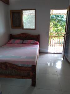 a bedroom with a bed in a room with a window at Hostal El Nido del Azulejo in Baru