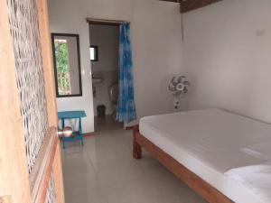 a bedroom with a bed and a bathroom with a fan at Hostal El Nido del Azulejo in Barú