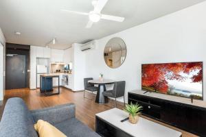 a living room with a couch and a tv and a table at Vibrant Inner City Living 1 bedroom Apartment in Brisbane