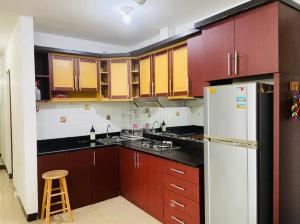 a kitchen with brown cabinets and a white refrigerator at Apartemen Paladian Kelapa Gading Syariah in Jakarta