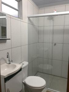 a bathroom with a toilet and a sink and a shower at Suítes Doce Lar in Paraty