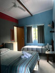 a bedroom with two beds and a blue wall at Suítes Doce Lar in Paraty