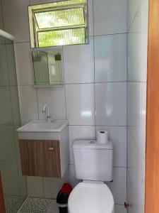 a bathroom with a toilet and a sink and a window at Suítes Doce Lar in Paraty