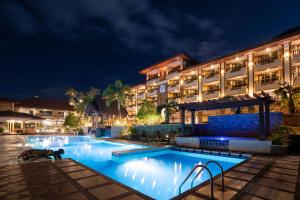 a hotel with a swimming pool at night at Coron Westown Resort in Coron