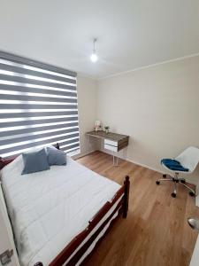 um quarto com uma cama, uma secretária e uma cadeira em Comodo Dpto. 4to piso - 2P/2B Excelente Conectividad/Buen Sector - Brisas Del Sol em Talcahuano