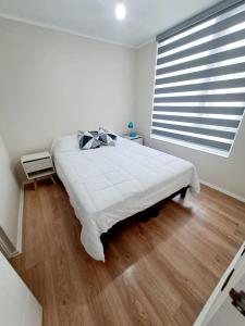 um quarto com uma grande cama branca e uma grande janela em Comodo Dpto. 4to piso - 2P/2B Excelente Conectividad/Buen Sector - Brisas Del Sol em Talcahuano