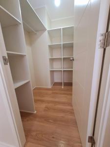 um closet com armários brancos e pisos de madeira em Comodo Dpto. 4to piso - 2P/2B Excelente Conectividad/Buen Sector - Brisas Del Sol em Talcahuano