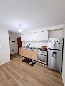 a kitchen with white cabinets and a stainless steel refrigerator at Comodo Dpto. 4to piso - 2P/2B Excelente Conectividad/Buen Sector - Brisas Del Sol in Talcahuano