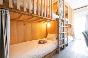 Etagenbett in einem kleinen Zimmer mit Leiter in der Unterkunft ZAITO Tokyo Kinshicho Economy Inn 宅东东京横川1民宿 in Tokio