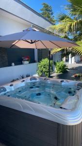 una bañera de hidromasaje situada bajo una sombrilla en un patio en Maison vue panoramique et accès SPA en La Réole