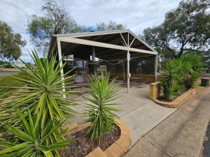 a pavilion with plants in front of a building at Spicer Caravan Park in Parkes