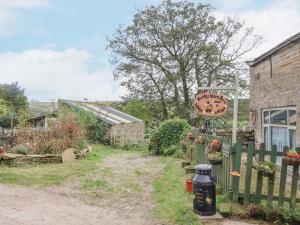 a garden with a fence and a sign at Moldy Warp Barn in Keighley