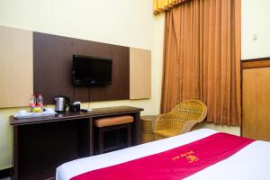 a hotel room with a bed and a desk with a tv at Urbanview Hotel Dedy Jaya Brebes in Brebes