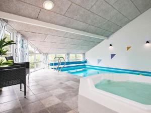 a swimming pool with a tub in a room at 12 person holiday home in Bl vand in Blåvand