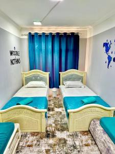 a bedroom with two beds and a blue curtain at Guest house by Sayohati Diyor in Dushanbe