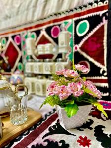 un jarrón lleno de flores rosas sentado en una mesa en Guest house by Sayohati Diyor en Dusambé