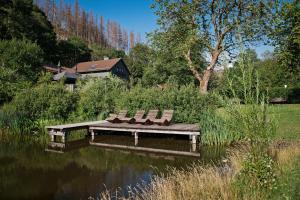trois chaises assises sur un banc au-dessus d'un étang dans l'établissement Green Tiny Village Harz - Tiny House Pioneer 7, à Osterode