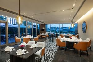 ein Restaurant mit Tischen, Stühlen und Fenstern in der Unterkunft Crowne Plaza Jiangmen Binjiang, an IHG Hotel in Jiangmen