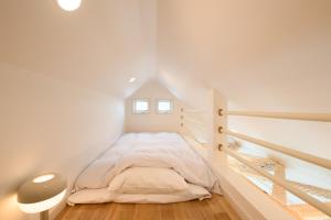 a white bedroom with a bed in a attic at 和光荘 Harmonious Light West in Hakone