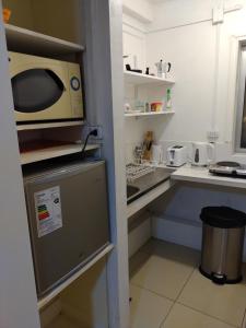 una pequeña cocina con microondas y fregadero en Hostal Renca, Casa Hotel, en Santiago