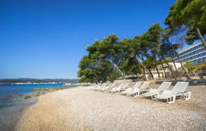 a row of white lounge chairs on a beach at Aminess Grand Azur Hotel in Orebić