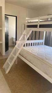Ce lit superposé blanc se trouve dans un dortoir doté d'une salle de bains. dans l'établissement Departamento en Acapulco Diamante MacMac, à Acapulco